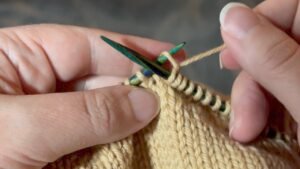 Inserting the needle into the back of the knit stitch